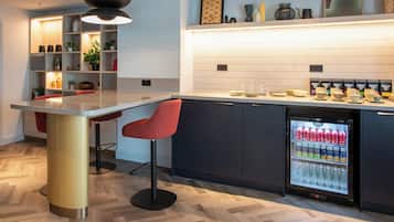 A modern kitchen with a central island, bar stools, a built-in refrigerator, and a tiled backsplash.