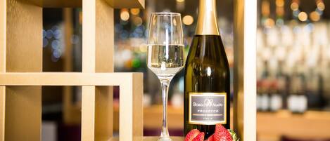 A bottle of Borgo Alato Prosecco and a glass on a wooden display.