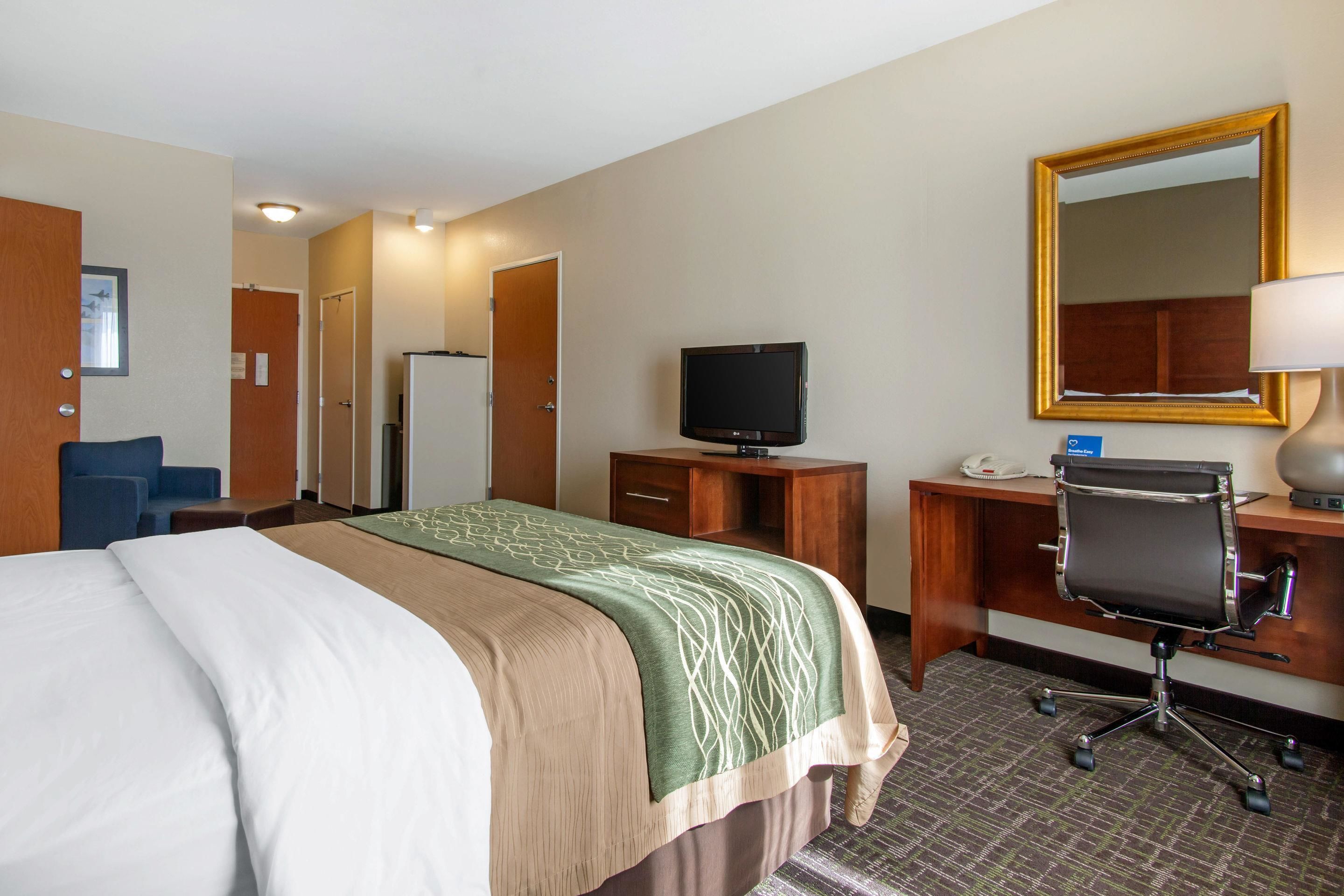 Une chambre d’hôtel équipée d’un lit, d’un bureau, d’une chaise, d’une télévision et d’un miroir.
