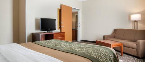 A hotel room with a bed, a TV, a desk, a chair, and a lamp.