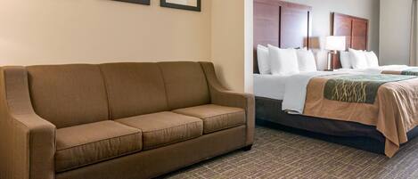 Una habitación de hotel con un sofá marrón, una cama con colcha marrón y una alfombra estampada.