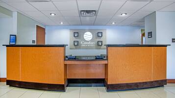 A reception area with a sign reading "Comfort Inn & Suites" and a digital display board.