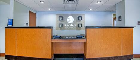 A reception area with a sign reading "Comfort Inn & Suites" and a digital display board.