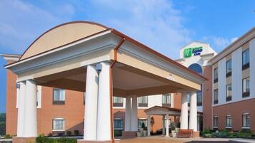 Ein Hotel mit überdachtem Eingang, blauem Himmel und einem Schild für Holiday Inn Express Suites.