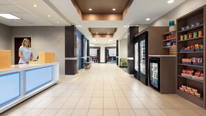 A hotel lobby with a reception desk, seating area, and snack shelves. - Holiday Inn Express & Suites Akron Regional Airport Area by IHG (Akron)