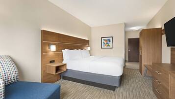 A hotel room with a bed, bedside table, lamp, wardrobe, and a television.