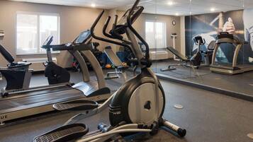 A gym with various exercise equipment including treadmills, ellipticals, and weights.