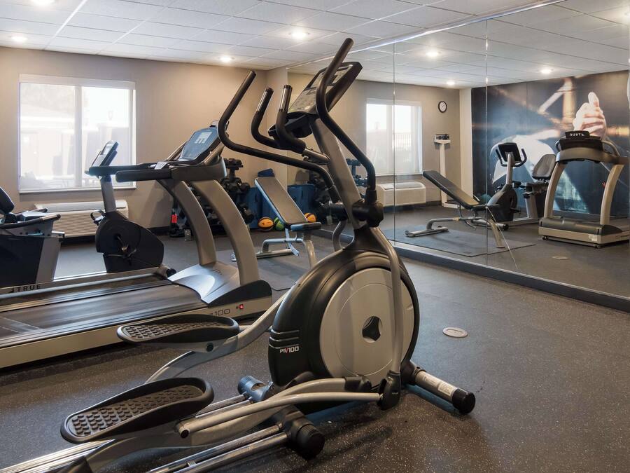 A gym with various exercise equipment including treadmills, ellipticals, and weights.