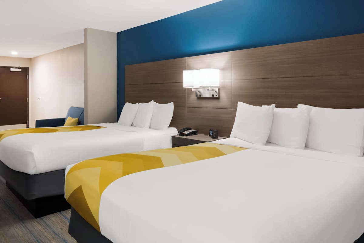 Ein Hotelzimmer mit zwei Betten, einem Nachttisch mit Telefon und einer Wandleuchte.