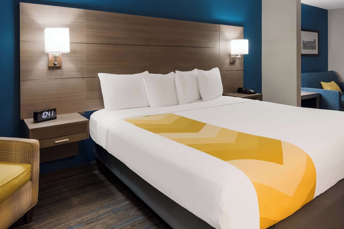 Ein Hotelzimmer mit einem großen Bett, zwei Nachttischen, einem Beistelltisch, einem Sessel und einer Wandleuchte.