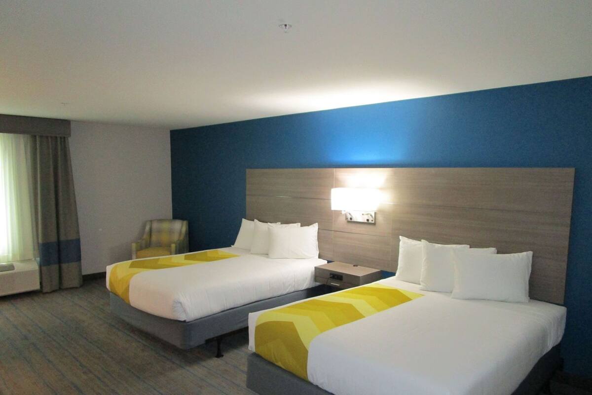 Ein Hotelzimmer mit zwei Betten, einem Sessel und einem Nachttisch.
