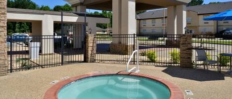 A hotel with a swimming pool, covered patio, and a parking area.