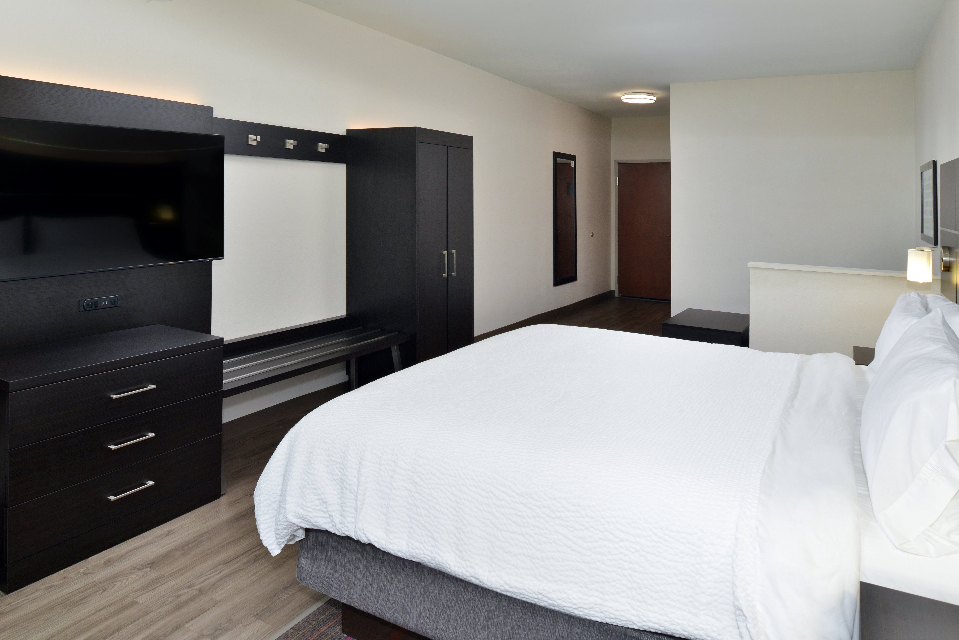 A hotel room with a bed, a TV, a wardrobe, and a desk.