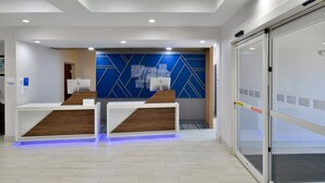 A reception area with two counters, a blue geometric wall design, and a glass door leading to a waiting area.