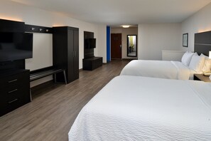 A hotel room with two beds, a TV, a desk, and a wardrobe.