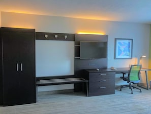 Une chambre moderne avec un grand lit, un bureau avec une chaise, un téléviseur à écran plat et un tableau encadré au mur.
