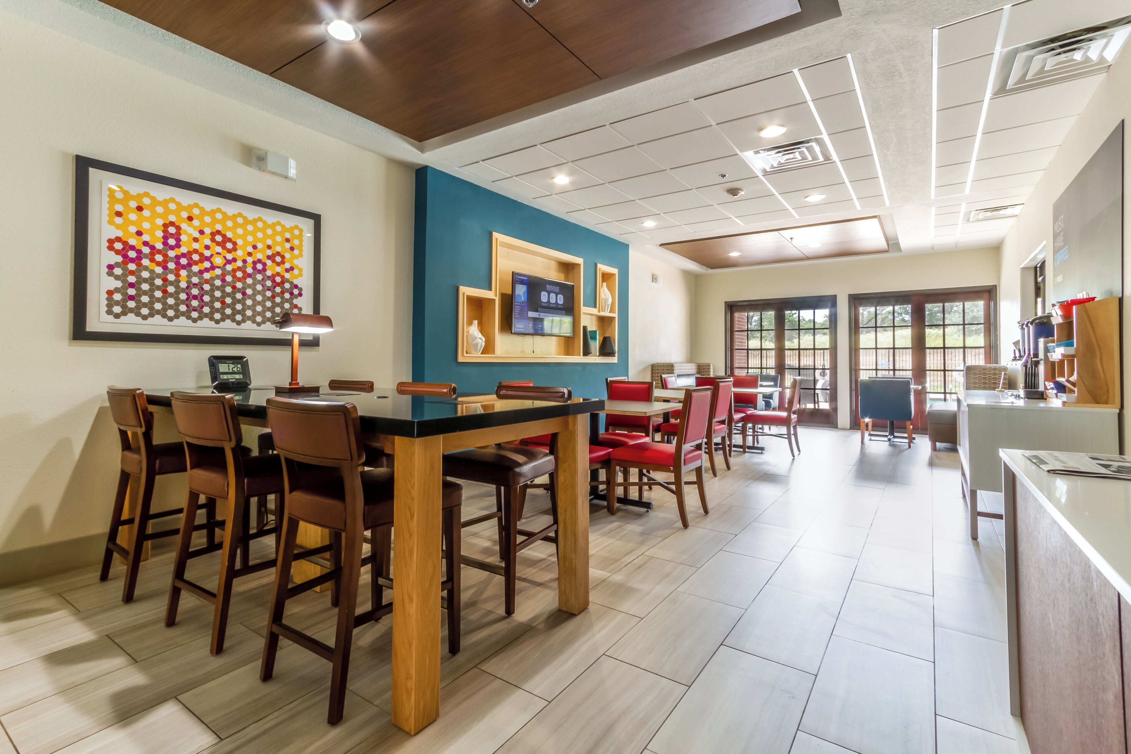 A restaurant with a long counter, wooden chairs, and a blue accent wall.