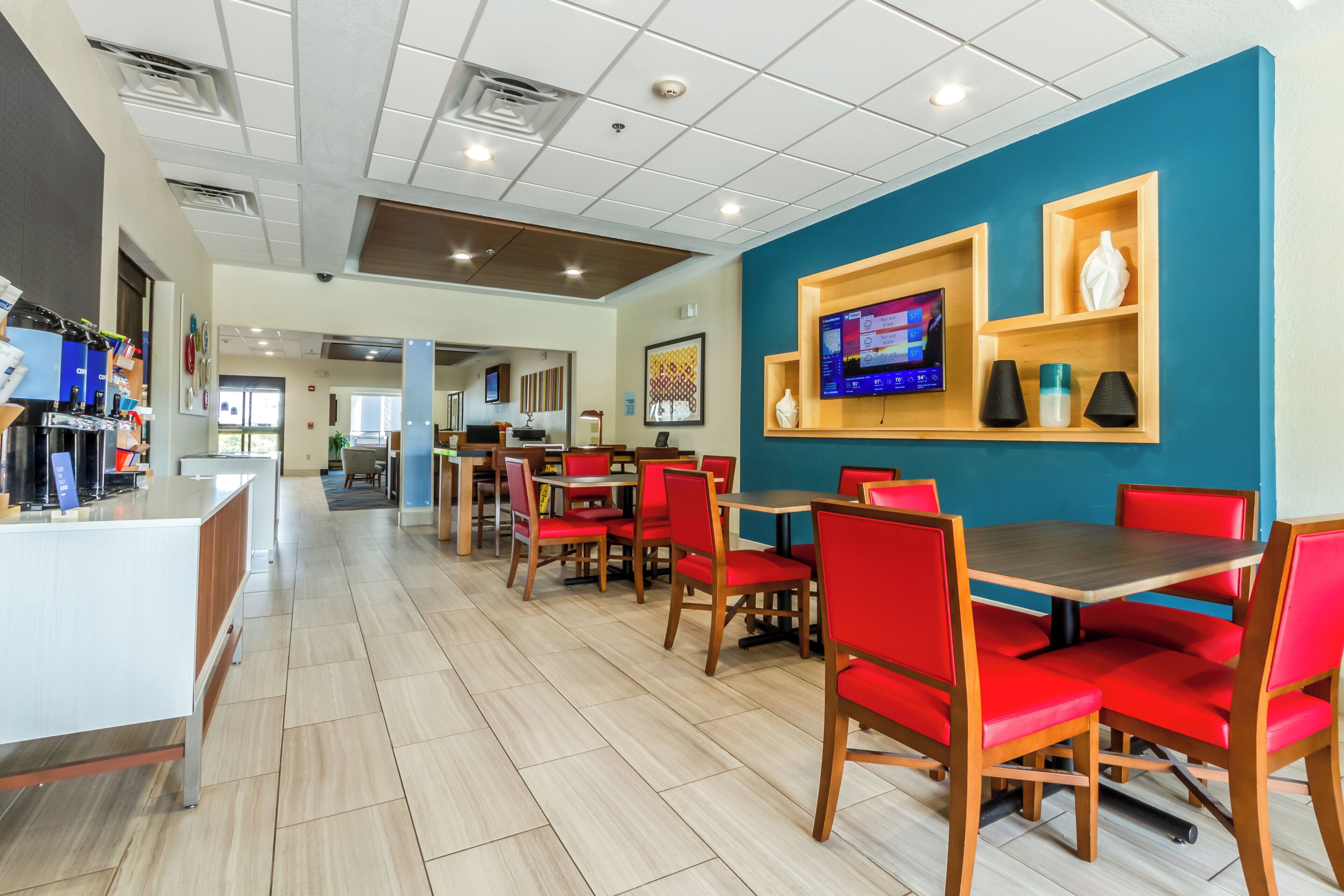 A modern restaurant with red upholstered chairs, a wooden counter, and a blue accent wall.