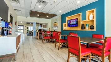 A modern restaurant with red upholstered chairs, a wooden counter, and a blue accent wall.