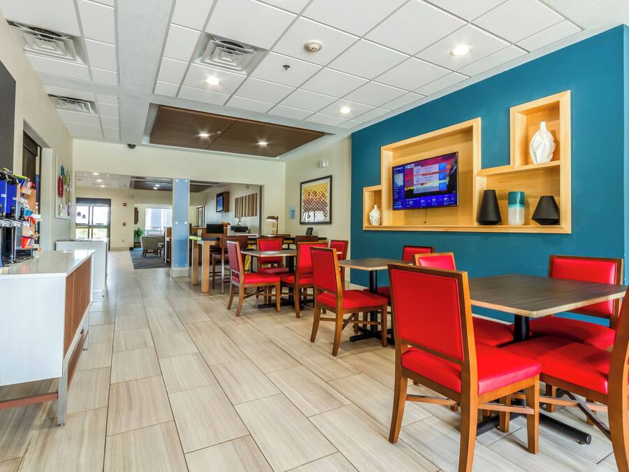 A modern restaurant with red upholstered chairs, a wooden counter, and a blue accent wall.