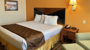 Une chambre d’hôtel avec un grand lit, une table de chevet avec une lampe, un téléphone et une chaise.