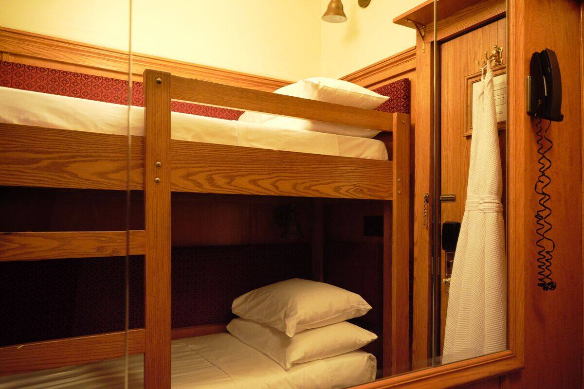 A bunk bed room with a wooden headboard, a telephone, and a towel hanging on the door.