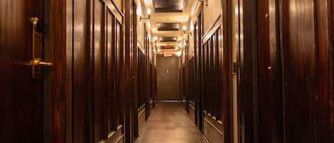 A long, narrow hallway with wooden doors on both sides, leading to a door at the end.