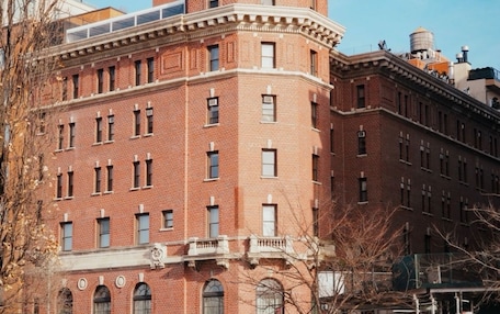 A multi-story brick building with a corner entrance, large windows, and a visible water tank on the roof.