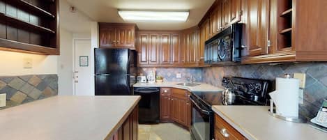 A kitchen with wooden cabinets, a black refrigerator, a microwave, a stove, and a dishwasher.
