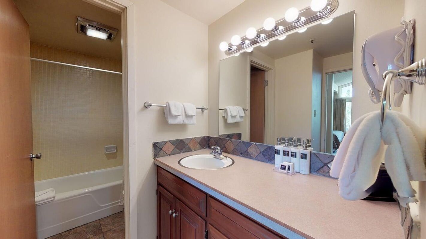 A bathroom with a bathtub, a sink, a vanity with a mirror, and a towel rack.