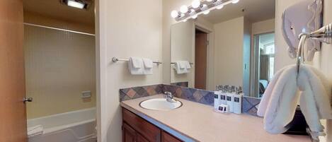 A bathroom with a bathtub, a sink, a vanity with a mirror, and a towel rack.