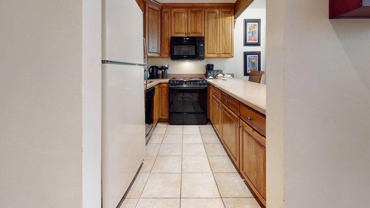 A compact kitchen with wooden cabinets, a black microwave, and a stove.