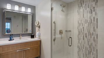 A modern bathroom with a glass-enclosed shower, a vanity with a mirror, and a sink.
