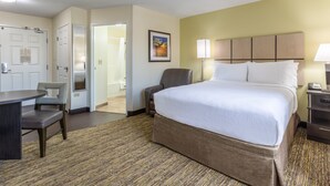 A hotel room with a bed, a desk, a chair, and a door leading to a bathroom. - Candlewood Suites Aurora-Naperville by IHG (Aurora)