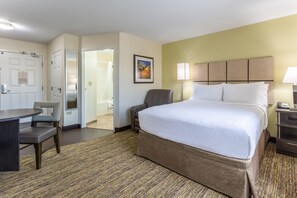 A hotel room with a bed, a desk, a chair, and a door leading to a bathroom. - Candlewood Suites Aurora-Naperville by IHG (Aurora)