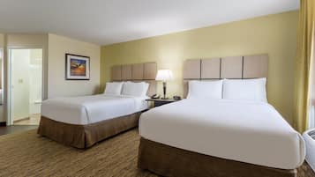 A hotel room with two beds, a nightstand, a lamp, and a painting on the wall.