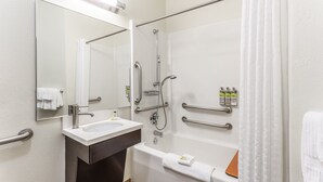 A modern bathroom with a sink, mirror, shower, and bathtub. - Candlewood Suites Aurora-Naperville by IHG (Aurora)