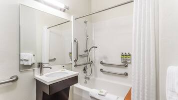 A modern bathroom with a sink, mirror, shower, and toilet.