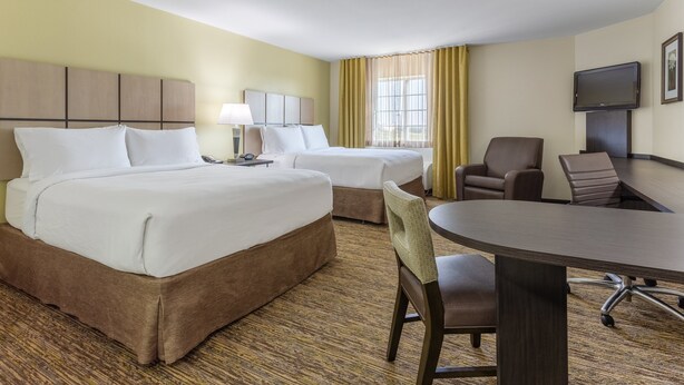 A hotel room with two beds, a desk, a chair, a television, and a window with curtains. - Candlewood Suites Aurora-Naperville by IHG (Aurora)