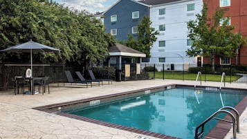Een buitenzwembad, parasols bij het zwembad en ligstoelen