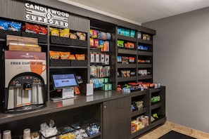 A self-service kiosk with snacks, a coffee machine, and a free cup offer sign.