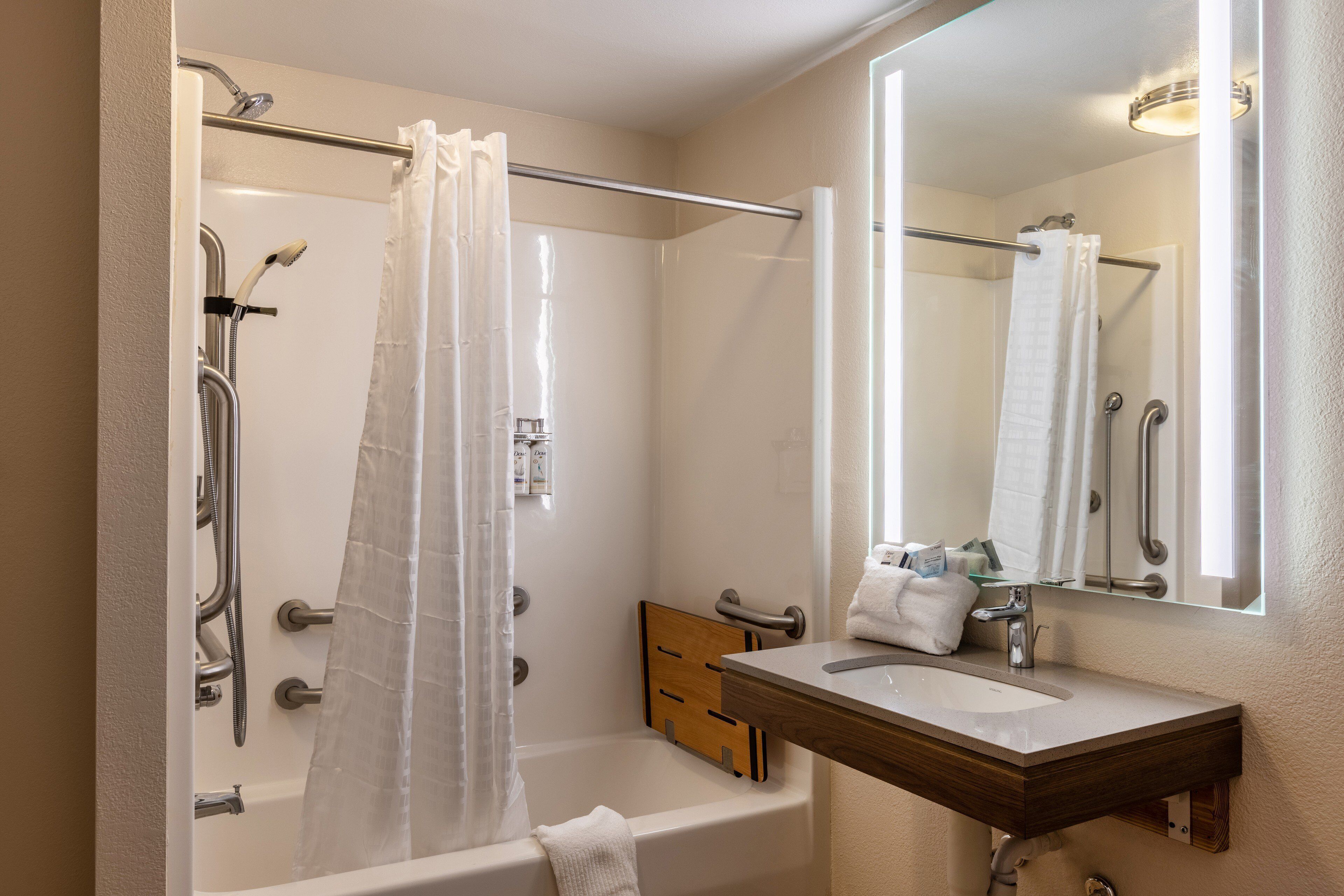 A bathroom with a bathtub, shower, and a vanity with a mirror.