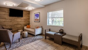 A modern living room with a sofa, armchairs, a coffee table, and a TV mounted on the wall. - Candlewood Suites Bluffton-Hilton Head by IHG (Bluffton)