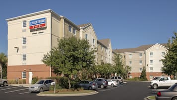 Un hotel con un cartel que dice "CANDLEWOOD SUITES" y un estacionamiento con varios autos.