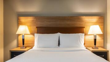 A hotel room with a large bed, two bedside tables, and two lamps.