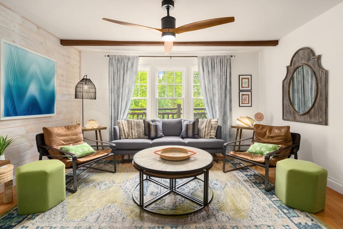 A cozy living room with a sofa, two armchairs, a coffee table, and a ceiling fan.