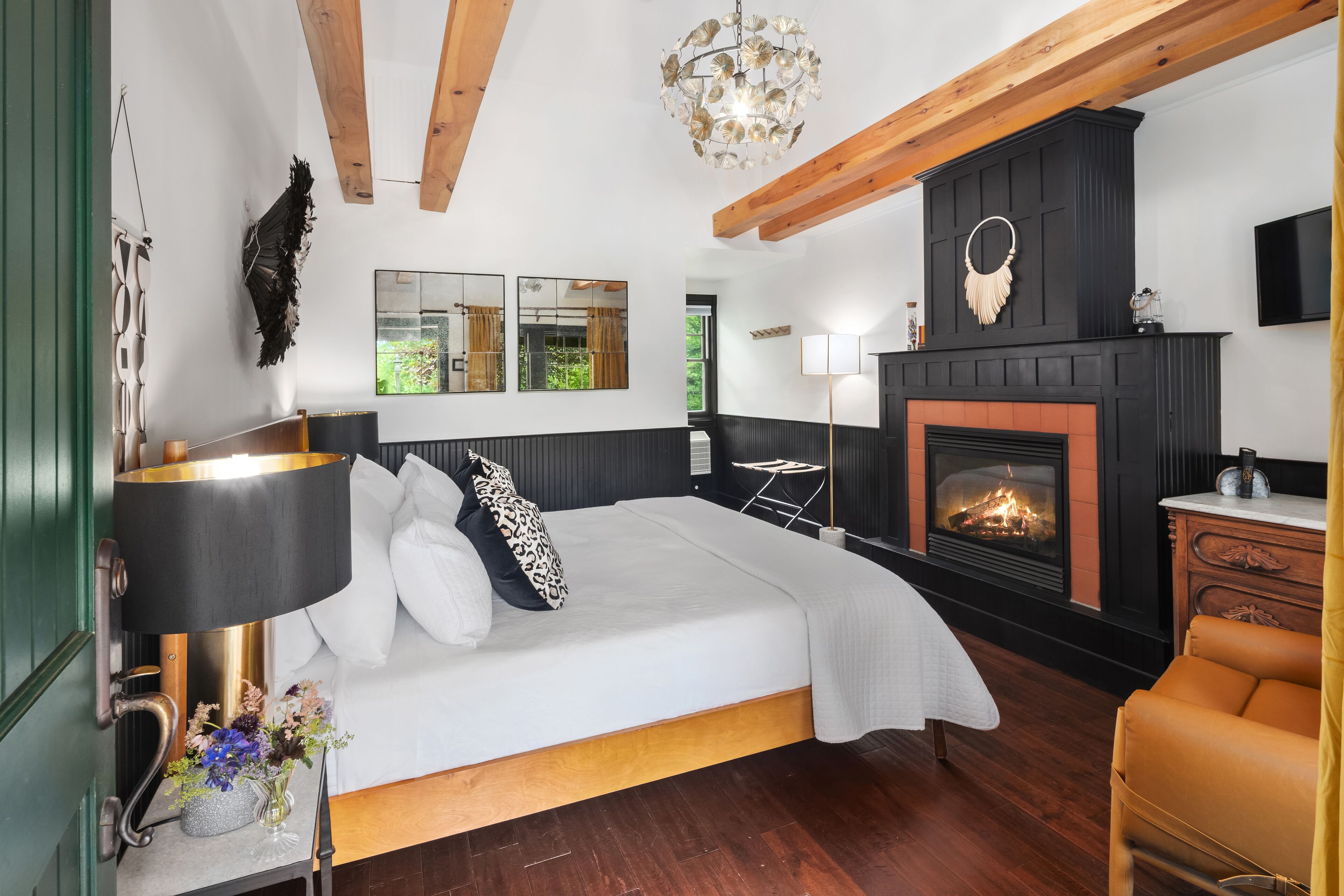 A bedroom with a bed, bedside table, lamp, and fireplace.