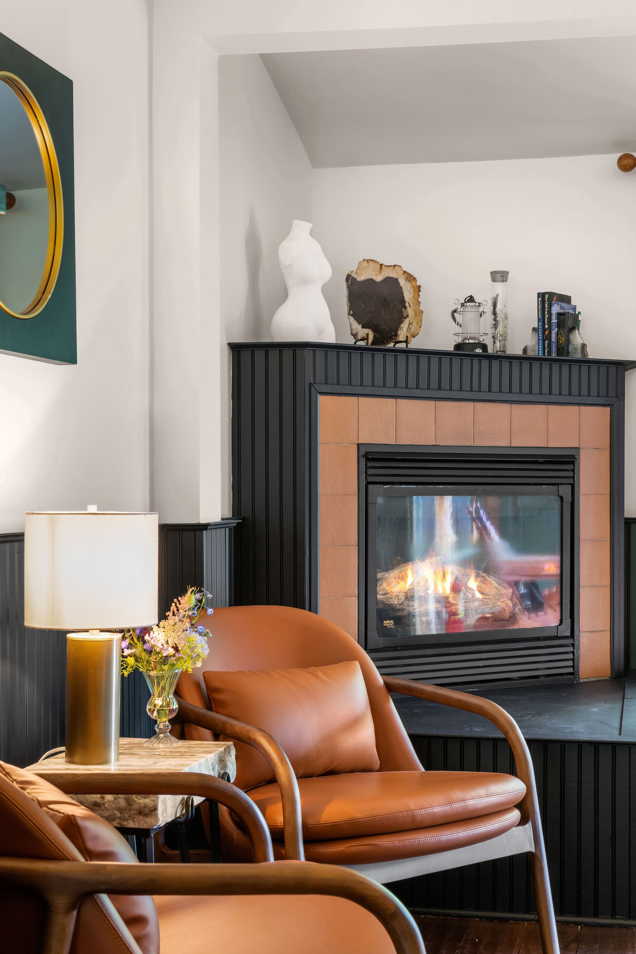 Una sala de estar moderna con chimenea, sillón de cuero y una mesa con un jarrón de flores.