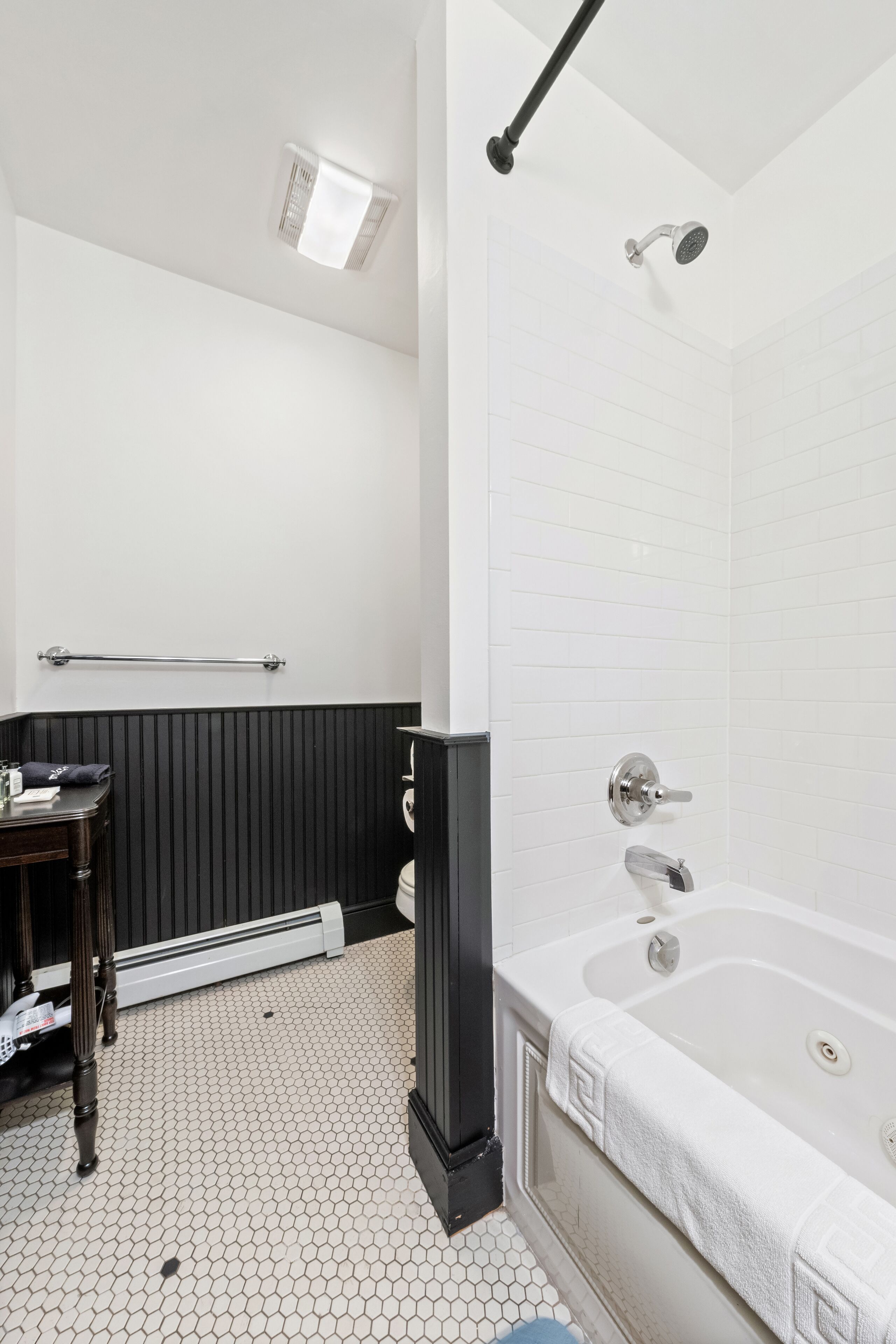 A bathroom with a white bathtub, a shower, a toilet, and a vanity with a mirror.