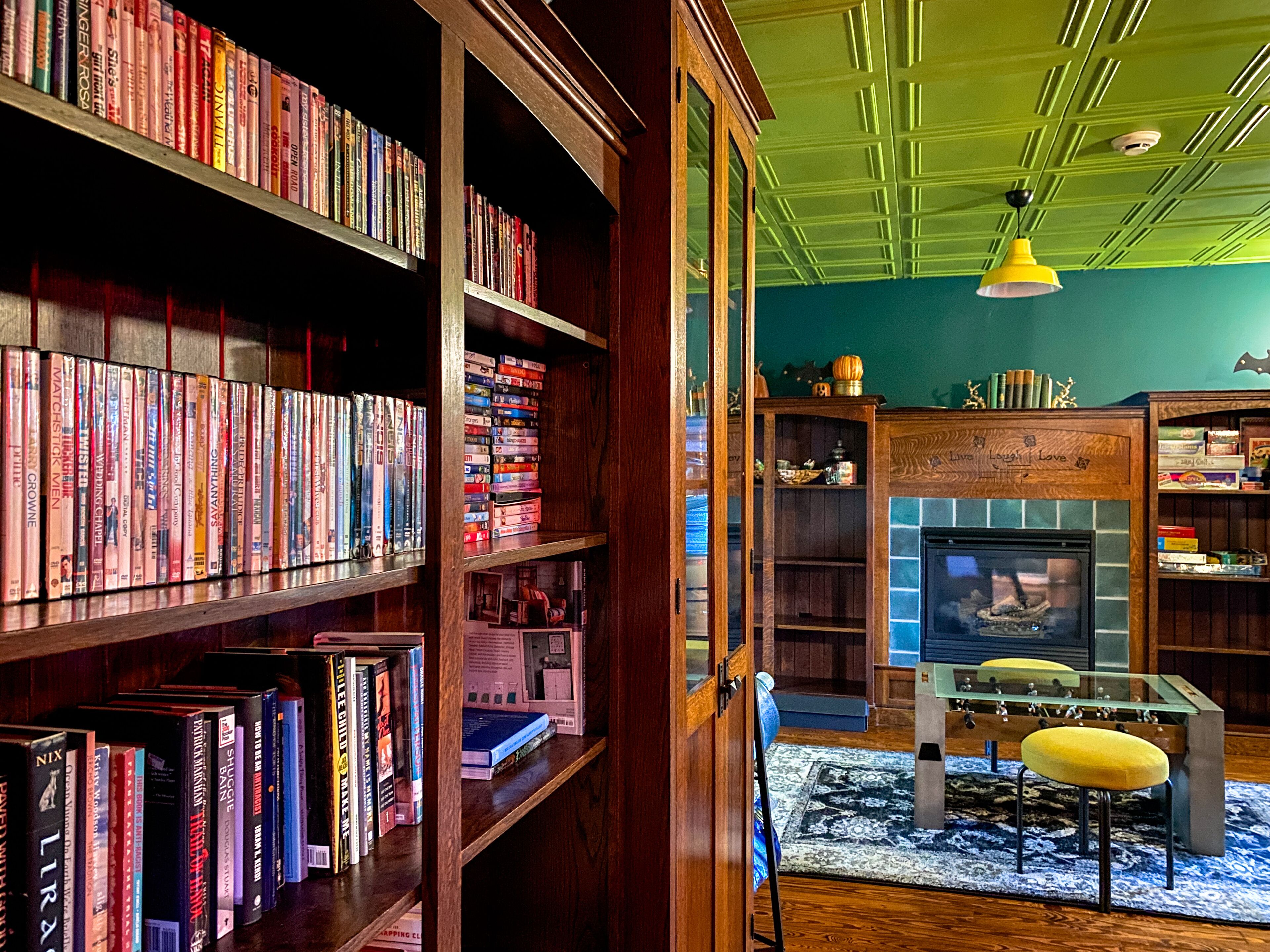 A library with bookshelves filled with books, a fireplace, and a television.